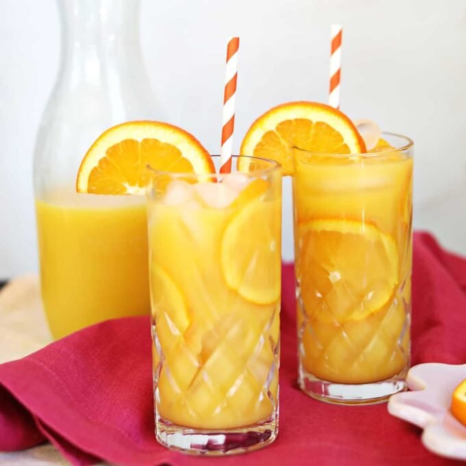 A refreshing Screwdriver cocktail in a tall glass, garnished with an orange slice, on a bright background.