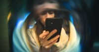 A hand holding a smartphone displaying an article in a clean, optimized reading mode, with a blurred background.