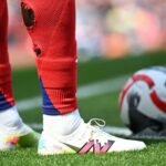 A soccer player on the field with visible holes cut into the calves of their athletic socks.