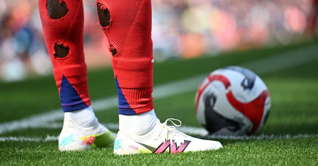 A soccer player on the field with visible holes cut into the calves of their athletic socks.