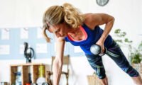 An older adult confidently lifting weights in a gym, demonstrating strength and vitality.