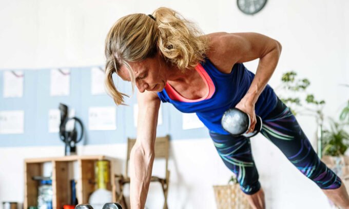 An older adult confidently lifting weights in a gym, demonstrating strength and vitality.