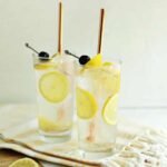 A tall, refreshing Tom Collins cocktail garnished with a lemon slice and a maraschino cherry.