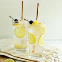 A tall, refreshing Tom Collins cocktail garnished with a lemon slice and a maraschino cherry.