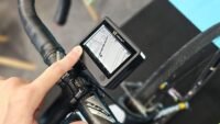Boîtier Velone fixé sur un guidon de vélo, affichant des informations de navigation.