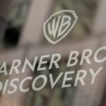 Warner Bros. Discovery and Amazon logos representing a legal dispute over executive hiring.