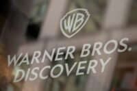 Warner Bros. Discovery and Amazon logos representing a legal dispute over executive hiring.