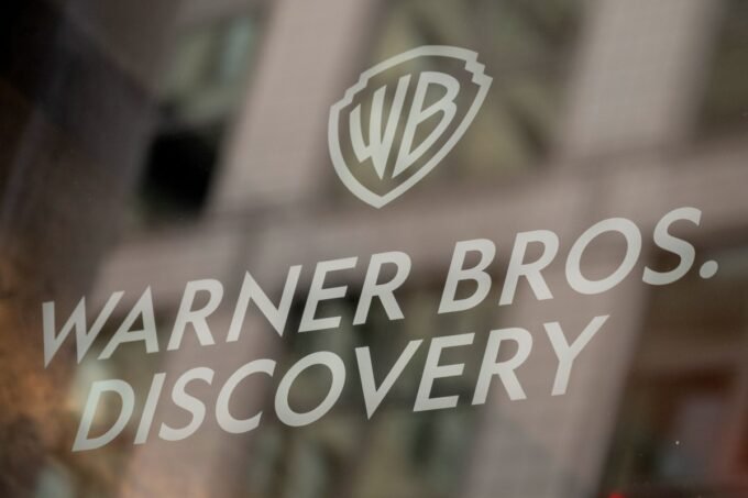 Warner Bros. Discovery and Amazon logos representing a legal dispute over executive hiring.