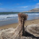 Vue aérienne d'Agadir avec sa plage, des hôtels et des palmiers, symbolisant la vitalité touristique de la ville.