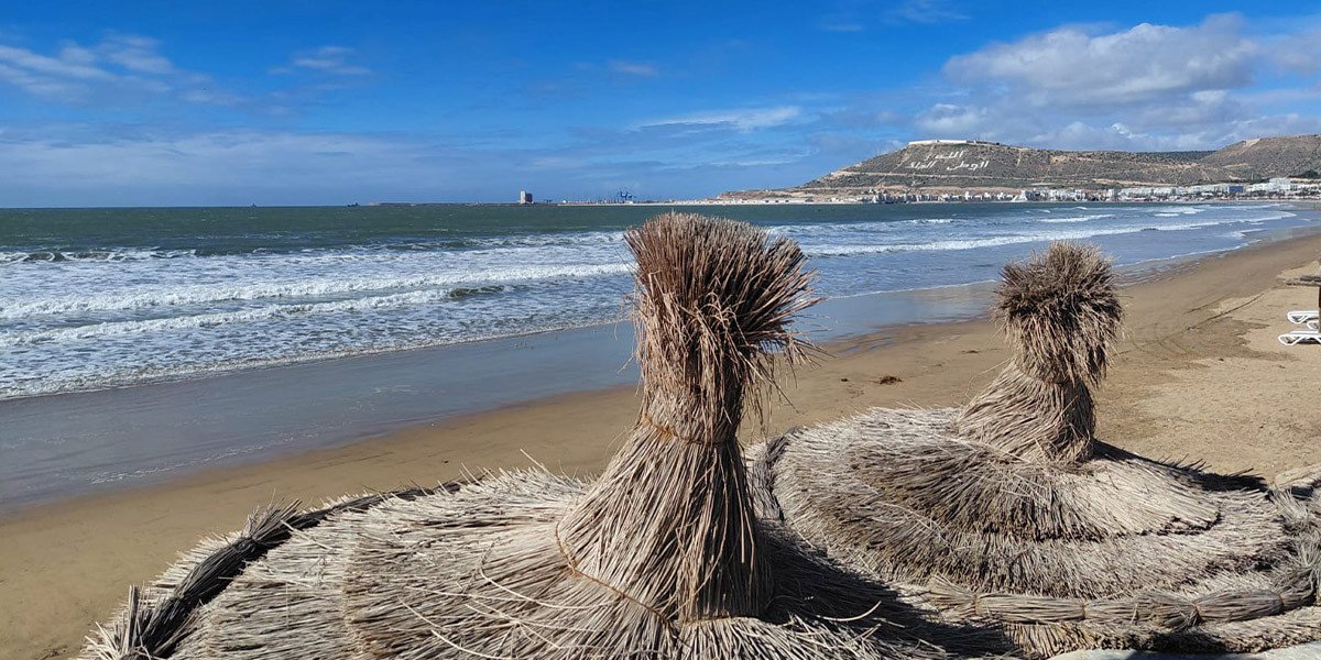 Agadir : L'Élan Touristique Ininterrompu, Un Succès Qui Se Confirme 3 Vue aérienne d'Agadir avec sa plage, des hôtels et des palmiers, symbolisant la vitalité touristique de la ville.