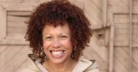Angela Nissel smiles, a thoughtful expression on her face, in a professional portrait.