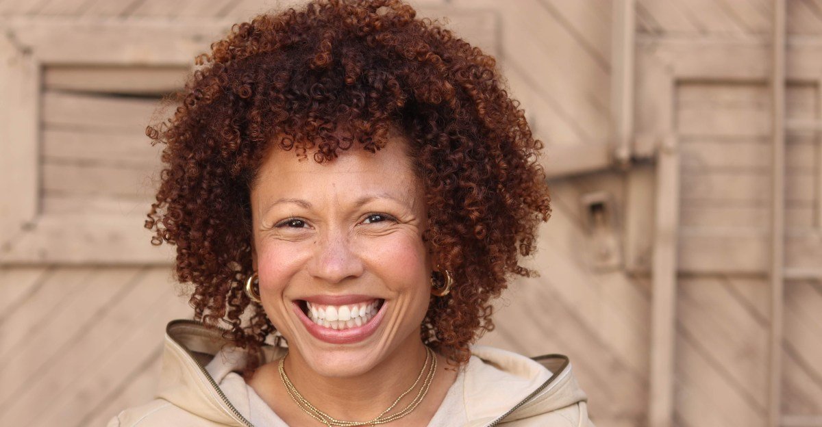 Angela Nissel smiles, a thoughtful expression on her face, in a professional portrait.