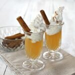 Delicious Apple Pie Shot garnished with whipped cream and a cinnamon stick, ready for autumn celebrations.