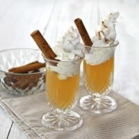 Delicious Apple Pie Shot garnished with whipped cream and a cinnamon stick, ready for autumn celebrations.