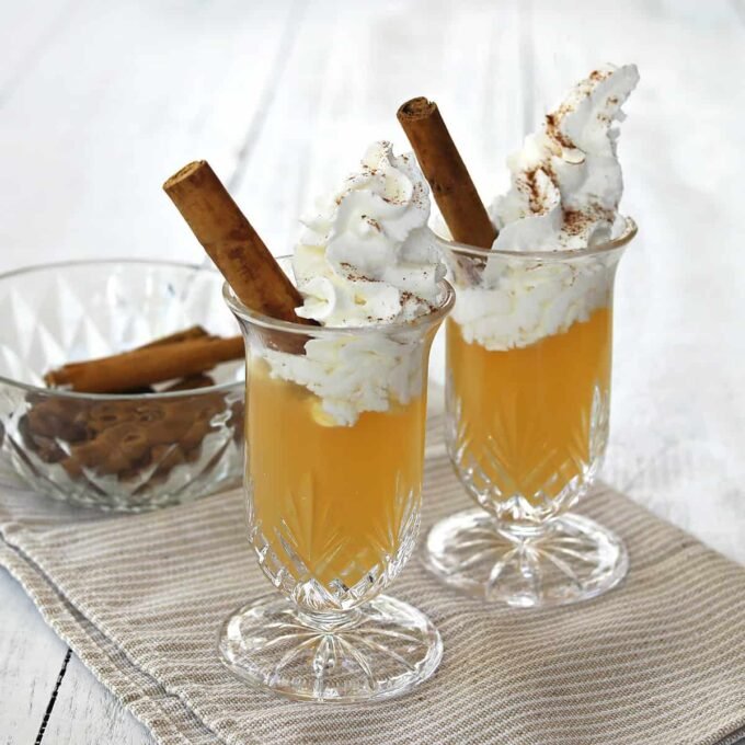 Sip into Autumn: The Irresistible Apple Pie Shot Recipe 5 Delicious Apple Pie Shot garnished with whipped cream and a cinnamon stick, ready for autumn celebrations.