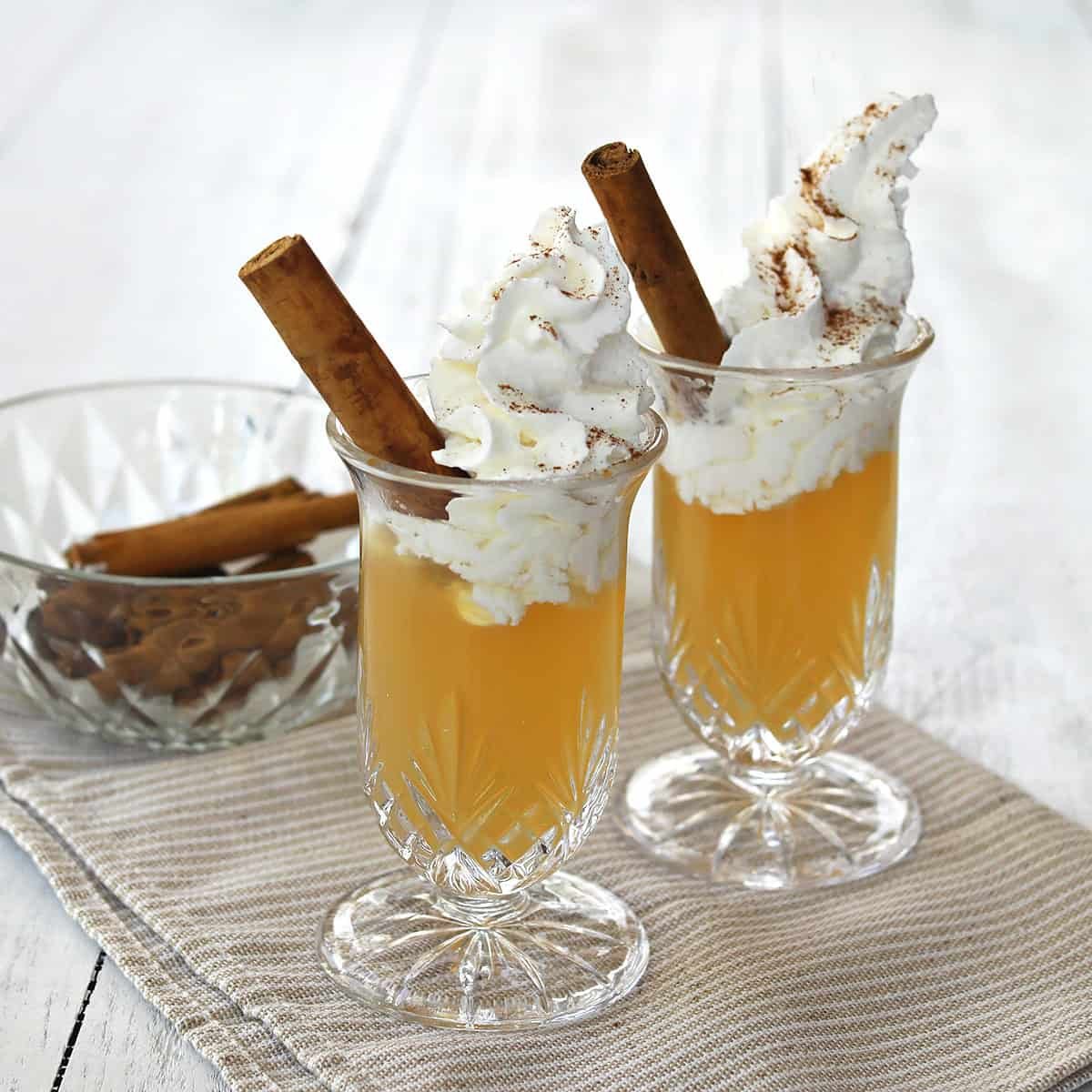 Delicious Apple Pie Shot garnished with whipped cream and a cinnamon stick, ready for autumn celebrations.