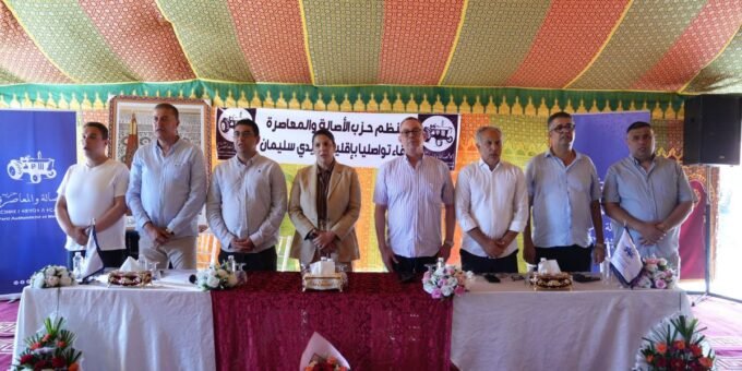 Fouzi Lekjaa et Fatima-Zahra Mansouri lors d'un rassemblement du PAM à Sidi Slimane, entourés de militants et de drapeaux du parti.