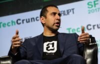 Balaji Srinivasan speaking at a tech conference, with a stylized 'Network School' logo in the background.