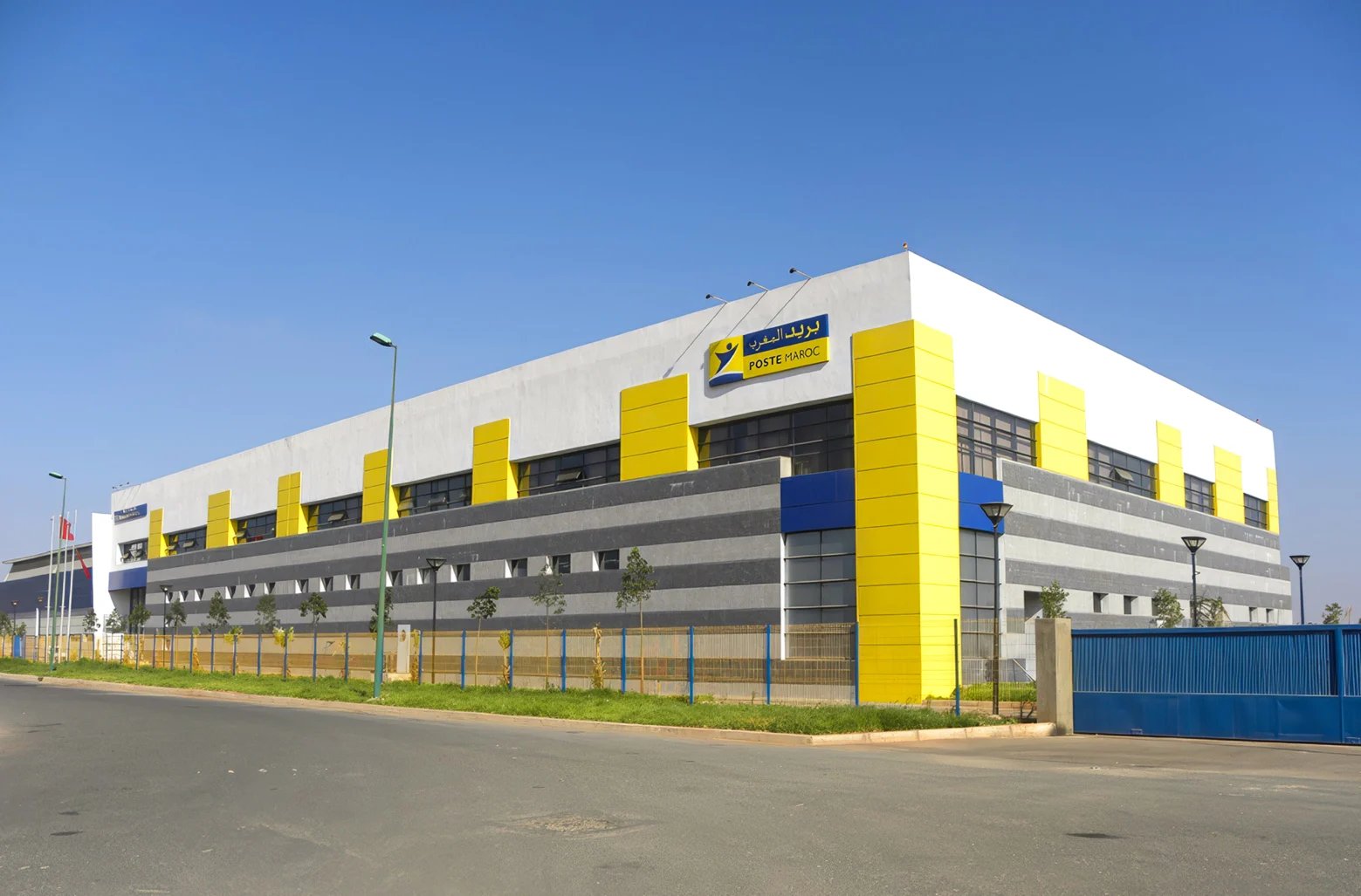 Barid Al-Maghrib : La Course au Tri Postal Automatisé S'accélère avec Quatre Finalistes 3 Vue aérienne d'un centre de tri postal moderne avec des machines de tri automatisées et des employés supervisant les opérations.
