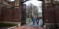Vue panoramique d'un campus universitaire américain emblématique, avec des étudiants marchant entre des bâtiments historiques sous un ciel nuageux, symbolisant les défis actuels de l'enseignement supérieur.