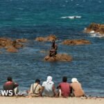 مهاجرون ينتظرون على الشاطئ في سبتة بإسبانيا، في 2 أغسطس/آب 2026
