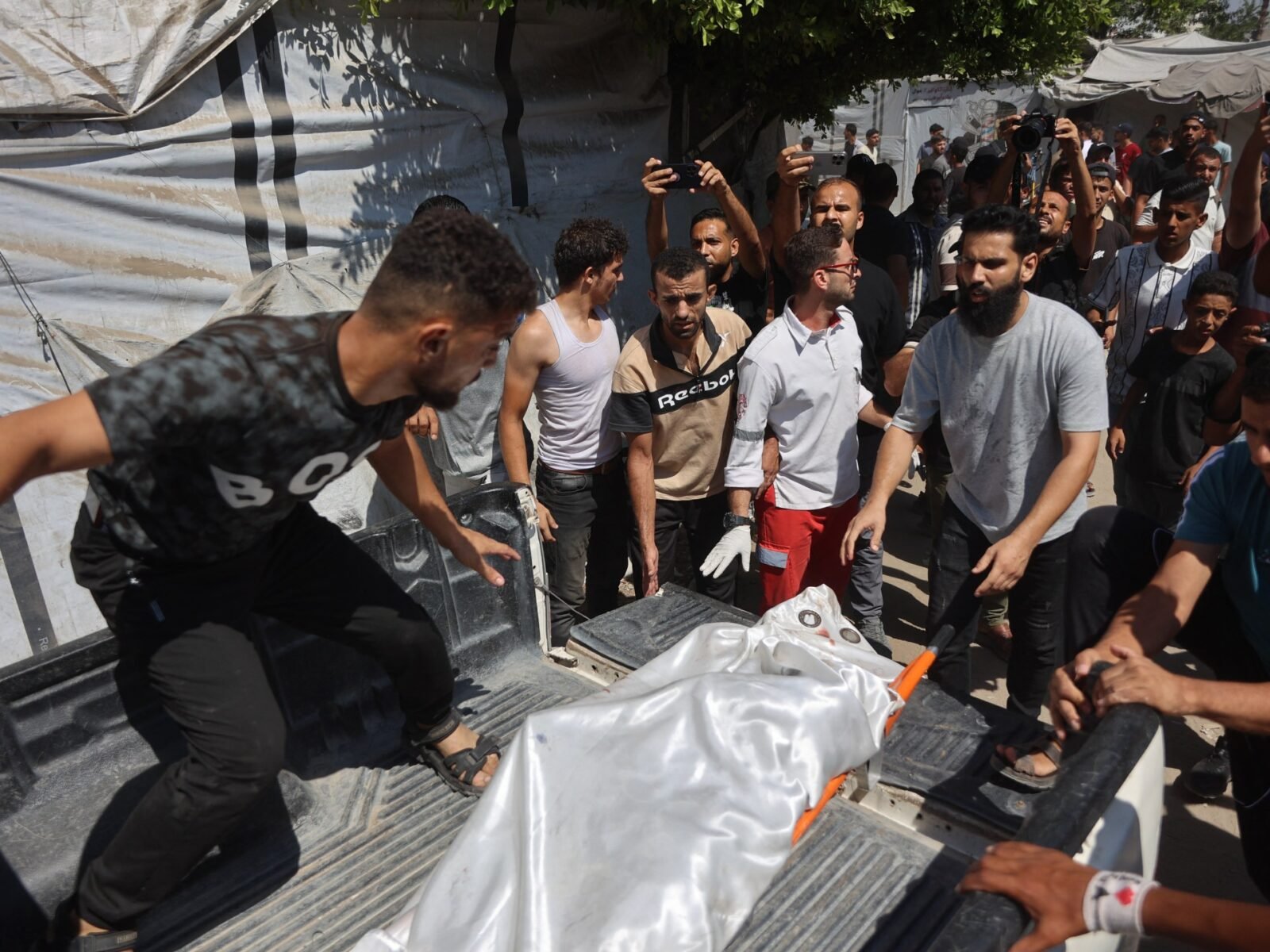 تصاعد التوتر في غزة: غارات إسرائيلية توقع 10 قتلى وسط إدانات حماسية 3 فلسطينيون يحملون جثمان ضحية بعد غارة إسرائيلية استهدفت مقر الشرطة البلدية في مدينة غزة.
