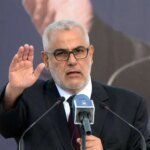 صورة تجمع بين شعار حزب العدالة والتنمية ورموز تشير إلى ملفات الأجور والتقاعد والتوظيف، مع خلفية تعكس أجواء الانتخابات.