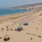 منظر بانورامي لشاطئ أكادير يعج بالمصطافين مع البحر الأزرق ورمال ذهبية