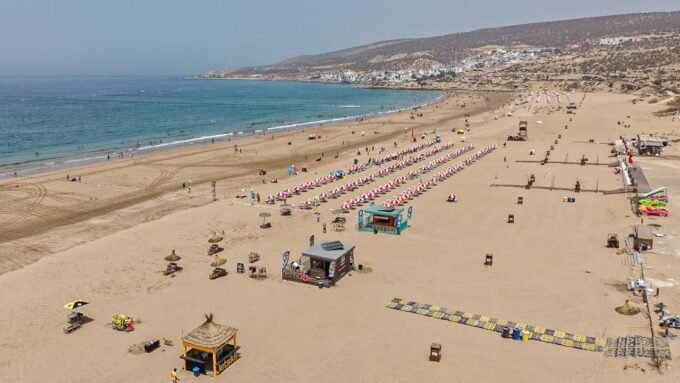 منظر بانورامي لشاطئ أكادير يعج بالمصطافين مع البحر الأزرق ورمال ذهبية