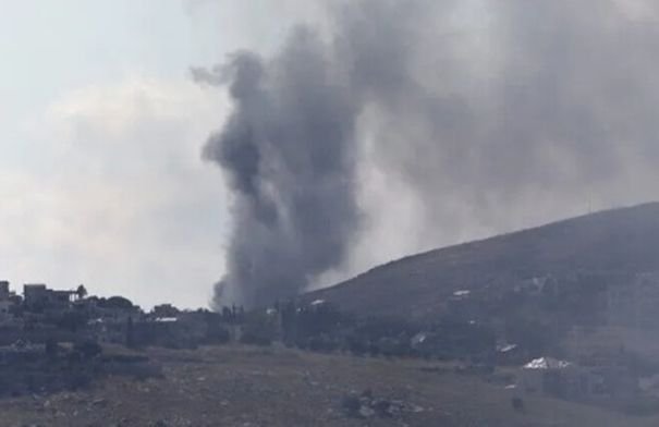 صورة جوية تظهر آثار غارة إسرائيلية على منطقة ريفية في جنوب لبنان، مع تصاعد للدخان.
