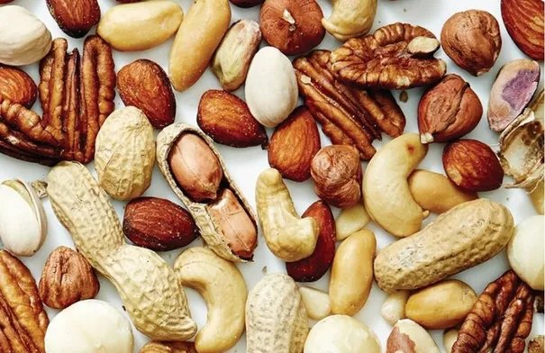 المكسرات: كنز غذائي يومي لتعزيز صحتك 4 تشكيلة من المكسرات المتنوعة مثل اللوز والجوز والكاجو والبندق، مصفوفة بشكل جذاب.
