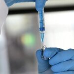 صورة توضيحية لعلماء يعملون في مختبر أبحاث السرطان، مع إشارة إلى جهود روسيا في تطوير لقاحات جديدة.