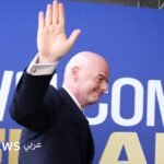صورة لرئيس الاتحاد الدولي لكرة القدم جياني إنفانتينو وهو يبتسم ويصافح شخصية أخرى في حفل توزيع جوائز.