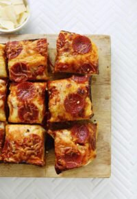 A square, golden-brown deep dish pizza with melted cheese, sauce, and toppings, cut into nine squares.