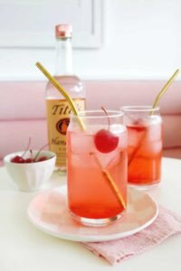 A vibrant red Dirty Shirley cocktail garnished with maraschino cherries and a lime slice in a tall glass.