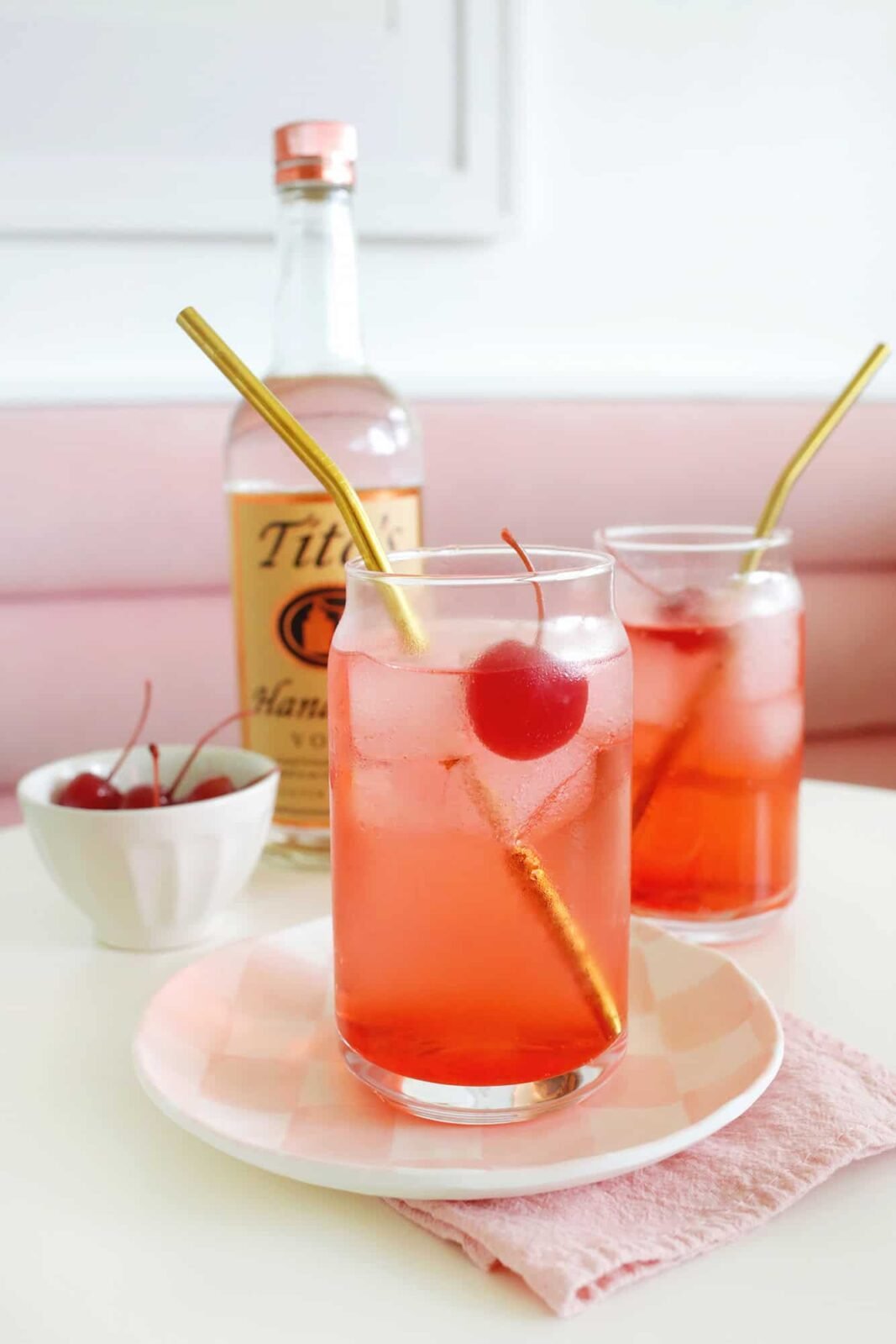 A vibrant red Dirty Shirley cocktail garnished with maraschino cherries and a lime slice in a tall glass.