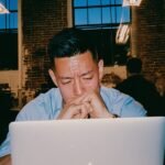 An entrepreneur staring at a blinking cursor on a laptop, symbolizing execution paralysis.
