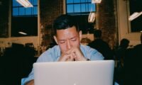 An entrepreneur staring at a blinking cursor on a laptop, symbolizing execution paralysis.