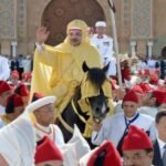 Le Roi Mohammed VI, accompagné du Prince Héritier Moulay El Hassan, du Prince Moulay Rachid et du Prince Moulay Ahmed, préside la cérémonie d’allégeance à la Place du Mechouar du Palais Royal de Tétouan, en commémoration de la Fête du Trône. Des officiels et des représentants des régions sont visibles, vêtus de tenues traditionnelles, dans un cadre solennel et majestueux.