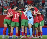Photo d'équipe des Lionnes de l'Atlas célébrant une victoire sur le terrain de football.
