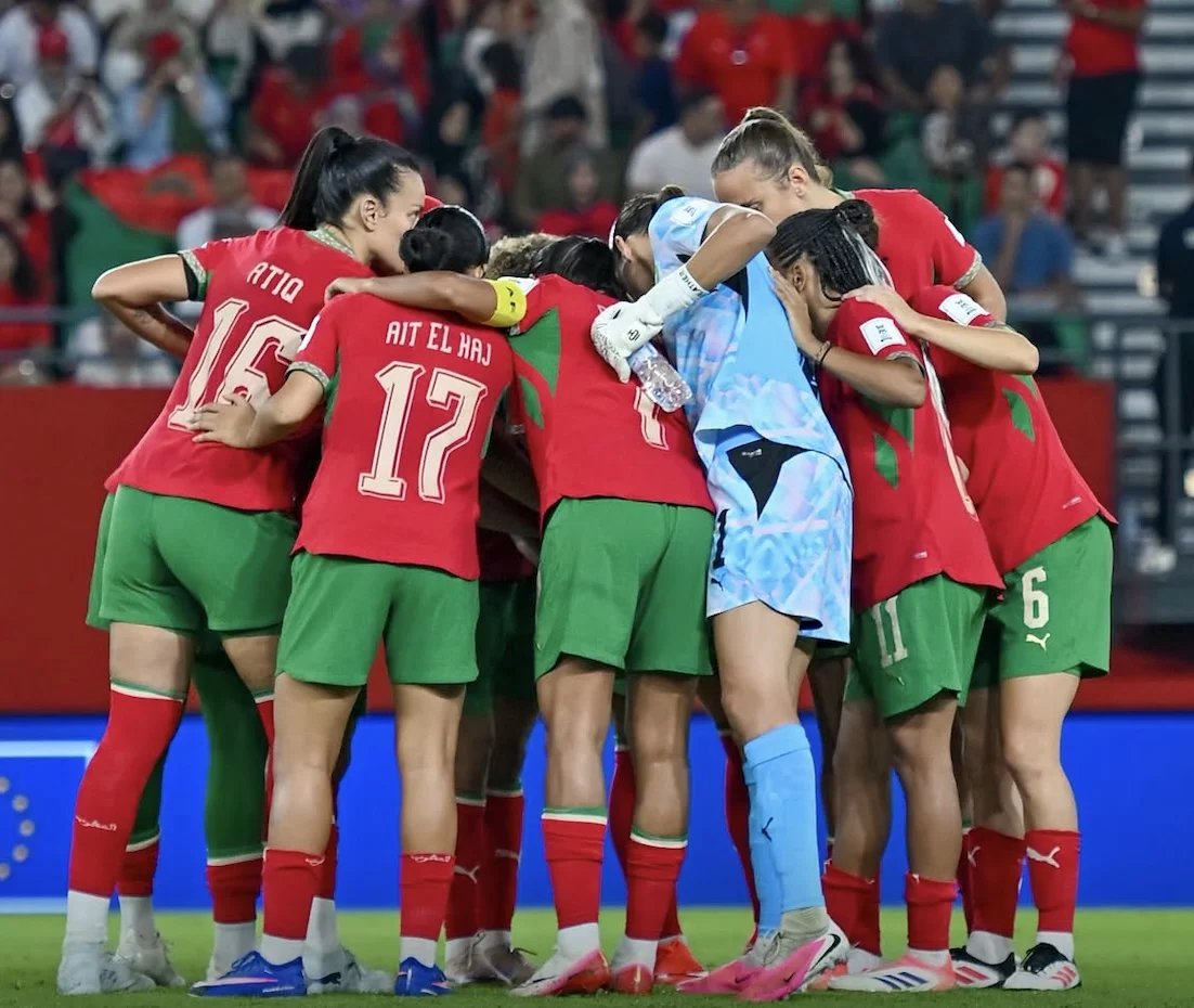 Photo d'équipe des Lionnes de l'Atlas célébrant une victoire sur le terrain de football.