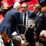 Des personnes âgées manifestant devant un bâtiment gouvernemental, symbolisant l'inquiétude face au gel des pensions de retraite.