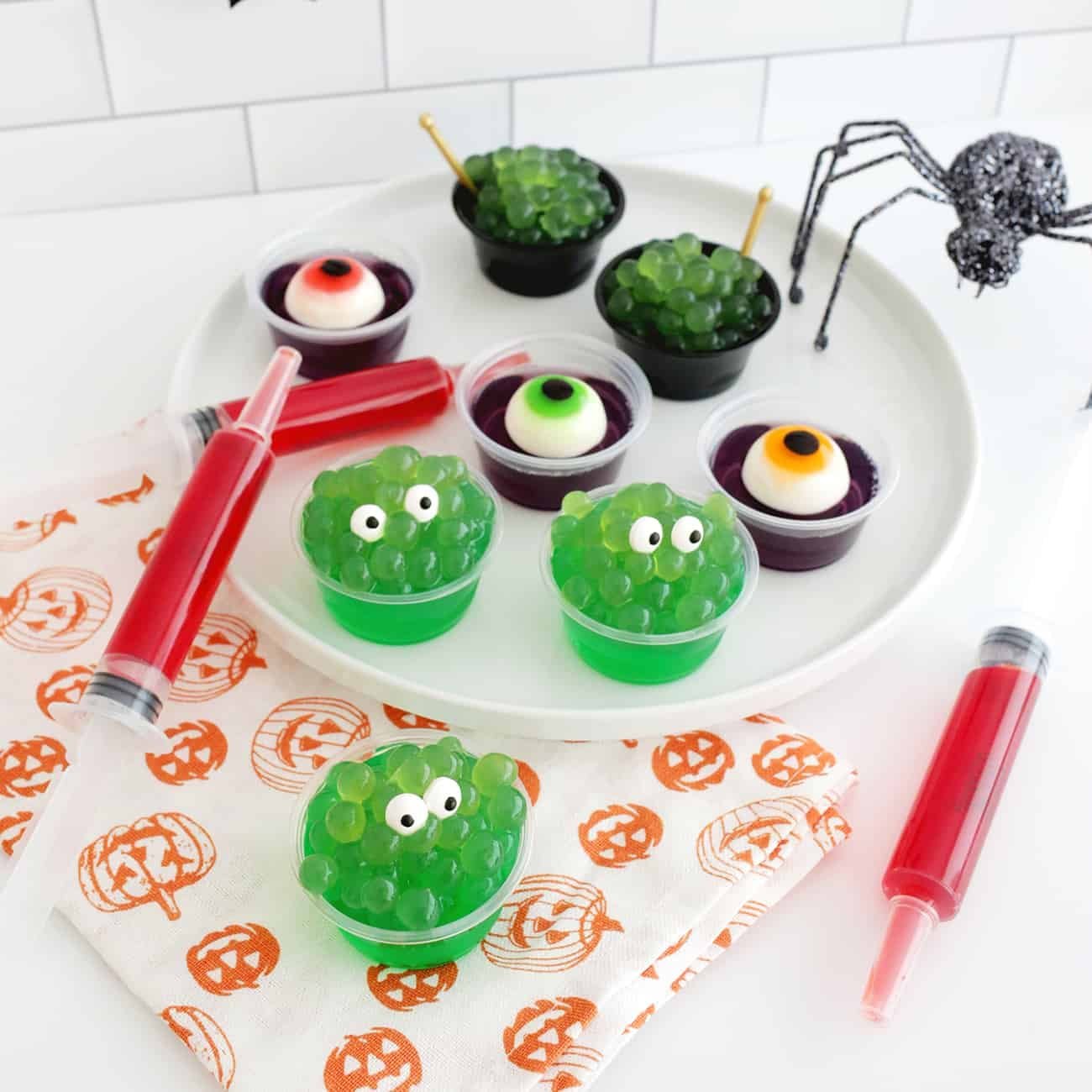 Spooktacular Sips: Crafting the Ultimate Halloween Jello Shots 3 A collection of vibrant Halloween-themed jello shots, including witch's cauldron, monster, eyeball, and syringe designs, ready for a party.