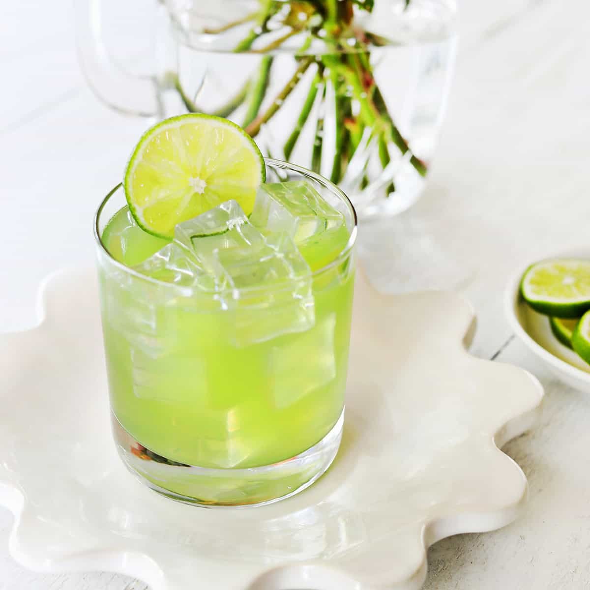 Vibrant green Incredible Hulk cocktail in a rocks glass with a lime garnish