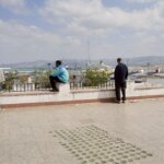Jeune homme marocain pensif, symbolisant la jeunesse inactive, avec un arrière-plan flou de ville marocaine.