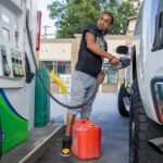 A person pumps gas at a Chevron gas station in Austin, Texas, highlighting rising fuel costs.
