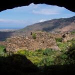 Vue panoramique du mont Gourougou, un ancien volcan près de Nador, avec ses falaises verdoyantes et des vestiges de tours en pierre au sommet, sous un ciel clair.