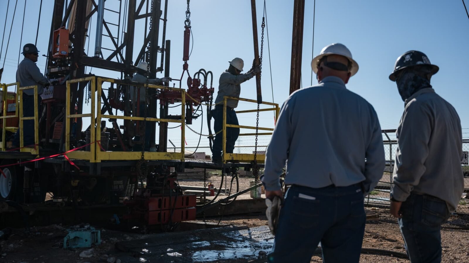 An oilfield crew operates a service rig during a state-funded oil well plugging operation in Midland, Texas.