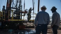 An oilfield crew operates a service rig during a state-funded oil well plugging operation in Midland, Texas.