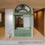 A modern, open-plan apartment in Barcelona featuring a central, arched bathtub integrated into the living space, designed by SIGLA Studio.